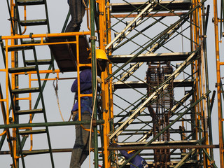 Construction workers working on scaffolding with blue sky at construction site