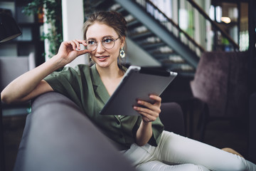 Woman with tablet smiling away sitting on couch