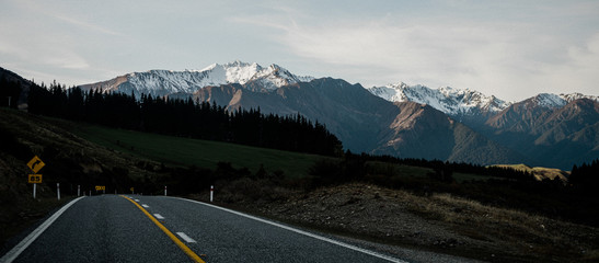 Beautiful sunset panorama of the Haast Pass road with snow capped mountains in the background on a winter day, New Zealand