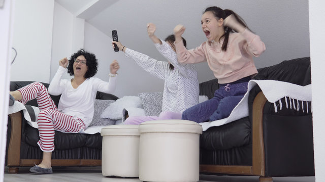 Family celebrationg sport game win. Mother watch TV chanelsat home with children in quarantine isolation Covid-19