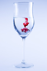 Powerful color splash in wine glass. Red ink, glass isolated.