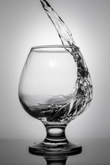 Clear liquid is poured into a beautiful glass on a white background