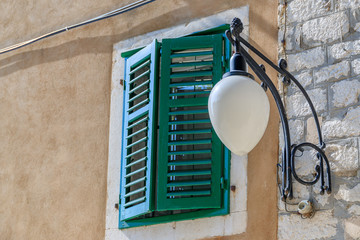 SIBENIK, CROATIA - 2017 AUGUST 18. Outdoor lamp next to a green window shutters in the street of...