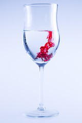 Powerful color splash in wine glass. Red ink, glass isolated.