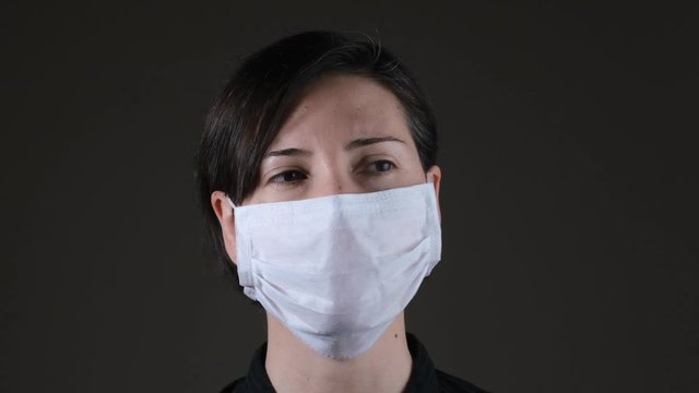 Portrait of a Caucasian woman wearing a white medical mask for protection against contagious disease, coronavirus