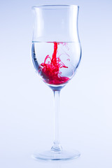 Powerful color splash in wine glass. Red ink, glass isolated.