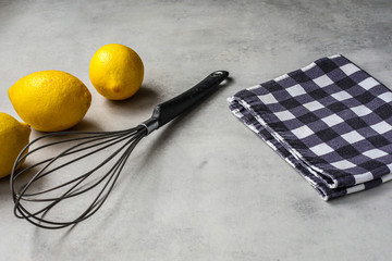Limones, batidora de huevos y mantel a cuadros sobre mesa