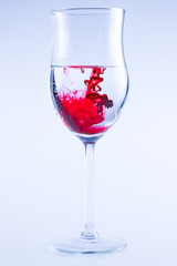 Powerful color splash in wine glass. Red ink, glass isolated.