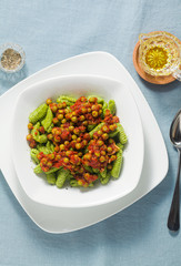 Italian fresh traditional sardinian pasta gnocchi with spinach and green pea tomato sauce. spring pasta for easter holidays.