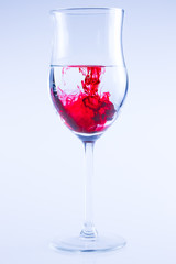 Powerful color splash in wine glass. Red ink, glass isolated.