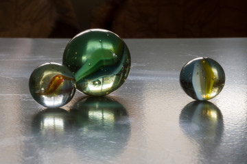 Three decorative colored glass balls with bubbles inside reflecting in icy surface. Concept of similar objects of different size or separate position of one.