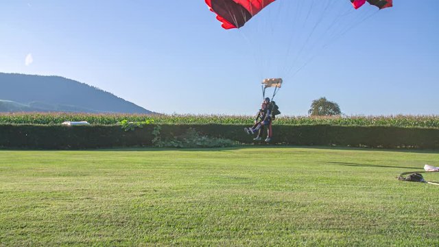 Tandem Skydivers Successfully Land Safely On The Ground By Parachute.
