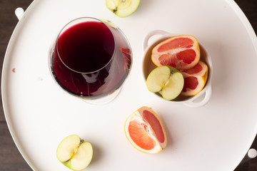 glass of red wine and fruits on a white table top view close-up 
