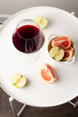 glass of red wine and fruits on a white table top view
