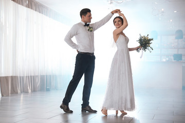 Happy newlywed couple dancing together in festive hall