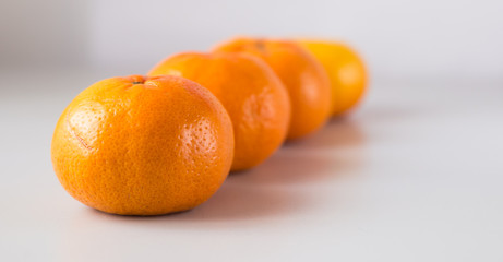 appetizing tangerines laid out in a row on white background