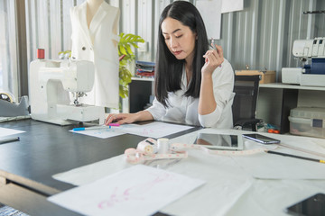 Young female fashion designer working on her designs in the studio. Fashion designer drawing...