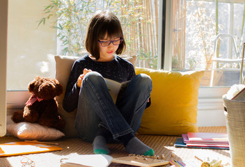 smiling child reading a book while virus lockdown, sunny balcony - 336998823