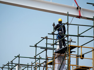 Construction workers working on scaffolding with blue sky at construction site