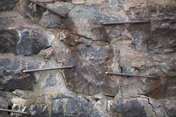 
Wall of a house made of large stones fastened with metal brackets