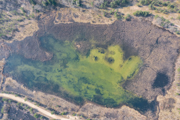Aerial top down view of lake between in forest and field