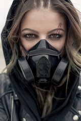 Fototapeta na wymiar Portrait of a young woman wearing a black respirator, posing outdoors