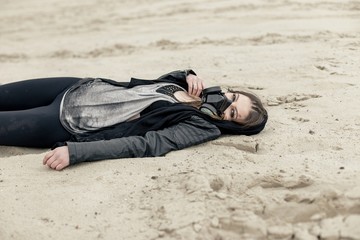 young woman with scarred face wearing respirator and  in urban dark clothes, posing outdoors
