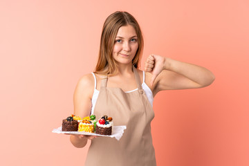 Pastry Ukrainian chef holding a muffins isolated on pink background showing thumb down sign