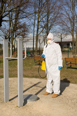 Obraz premium Kobieta w kombinezonie ochronnym dezynfekuje sprzęt sportowy w parku