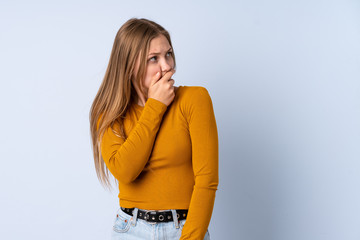 Teenager Ukrainian girl isolated on blue background having doubts and with confuse face expression