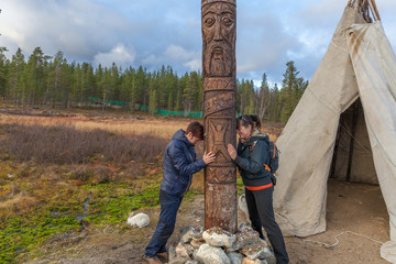 two women ask the gods of happiness, health, wealth in alley of the gods, Sami, saami village on the Kola Peninsula, Russia. Tourist ethnographic parking. Settlement Old Titovka, Murmansk region.