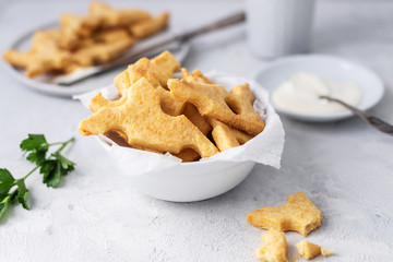 Cheese crackers, salty snack concept. Cookies, piece of cheese on a gray background