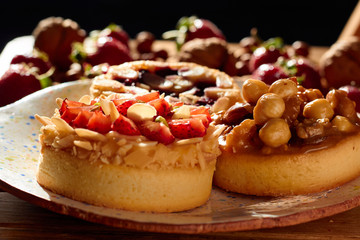 Three mini tarts cupcakes with strawberries, walnuts, almond, nuts and blueberries on plate