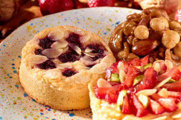 Three mini tarts cupcakes with strawberries, walnuts, almond, nuts and blueberries on plate