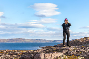 Obraz premium A middle-aged woman taking pictures standing on the rock. travel concept