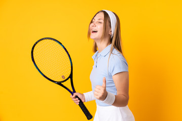 Teenager Ukrainian girl tennis player isolated on yellow background playing tennis and celebrating a victory