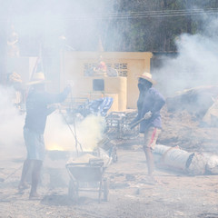 Obraz premium Unidentified workers are working in haze areas that are harmful to health, dust value PM 2.5. Pollution causes global warming. Workers preparing to smelt gold for casting Buddha statues