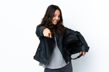 Young woman holding a motorcycle helmet over isolated white background making phone gesture and pointing front