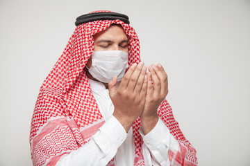 Arab man wearing corona virus mask and praying