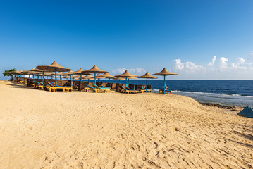 Sandy beach with deck chairs and straw umbrellas, Red Sea near Marsa Alam, Egypt, Africa