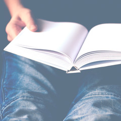 Men's hands hold a white book with clean pages