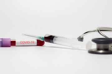 Coronavirus(Covid-19) blood sample vacuum tube and injection syringe with stethoscope on white...