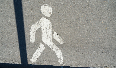 A white man drawn on asphalt walking from left to right.