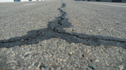 A large black crack in the asphalt diverges in three directions.