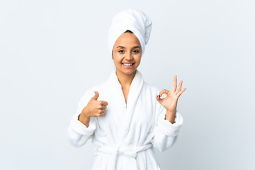 Young woman in bathrobe over isolated white background showing ok sign and thumb up gesture