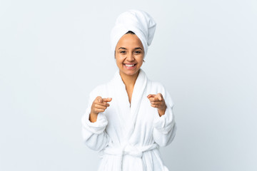 Young woman in bathrobe over isolated white background surprised and pointing front