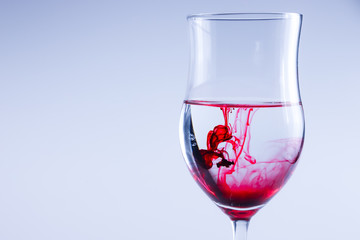 Red liquid splash in water. Wine glass isolated.