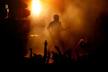Silhouette of the guitarist on stage over the fans.