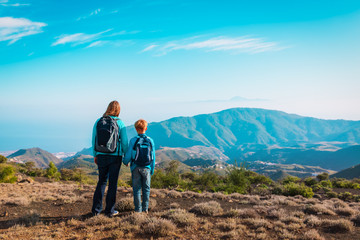 family travel- mother and son hiking in mountains