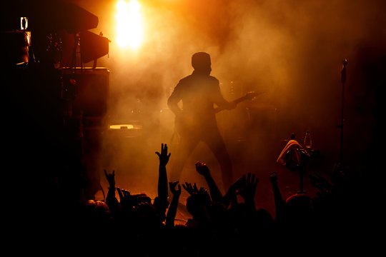 Silhouette of the guitarist on stage over the fans.